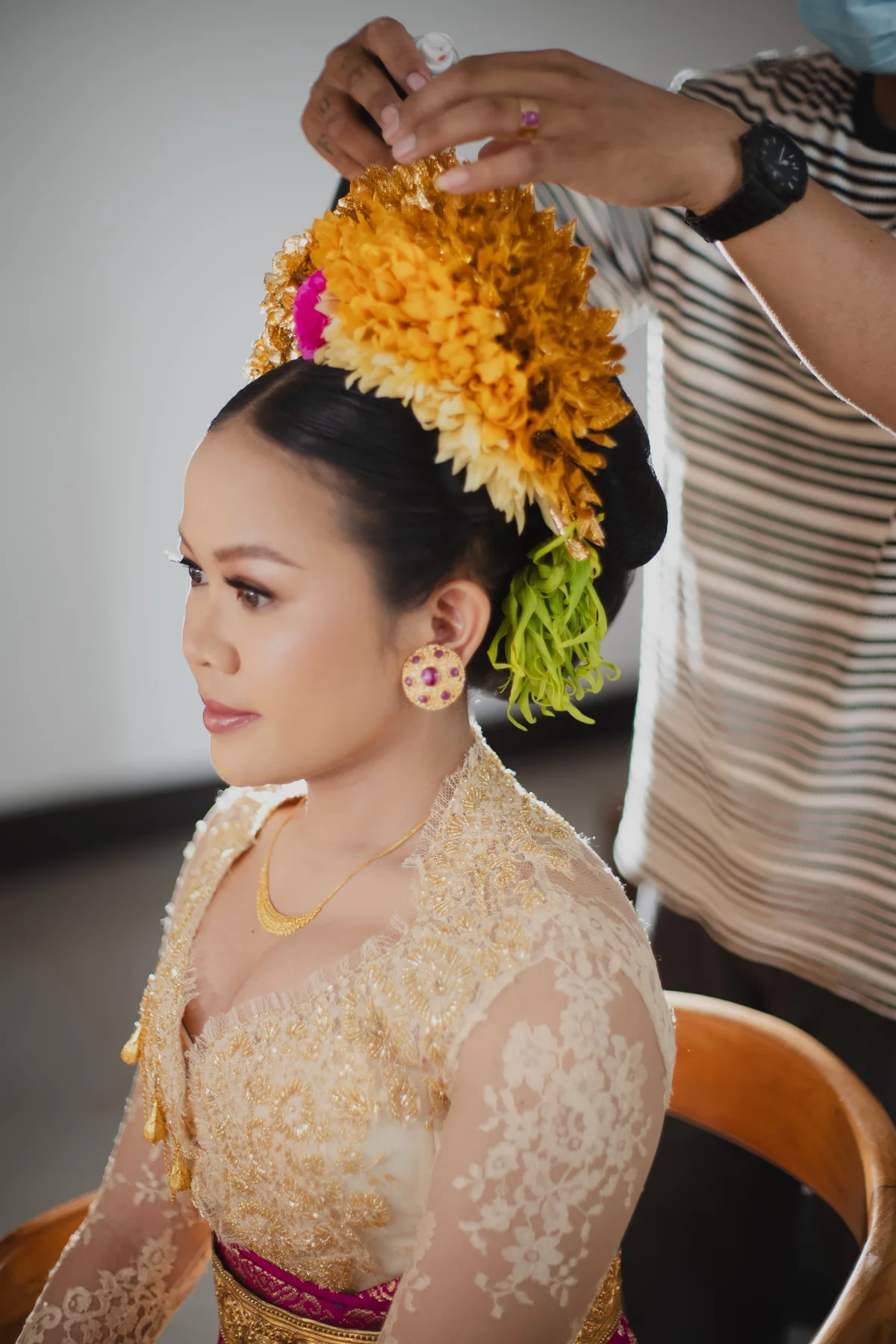 Gold floral bridal hair accessories being adjusted above a bride’s swept-up hair