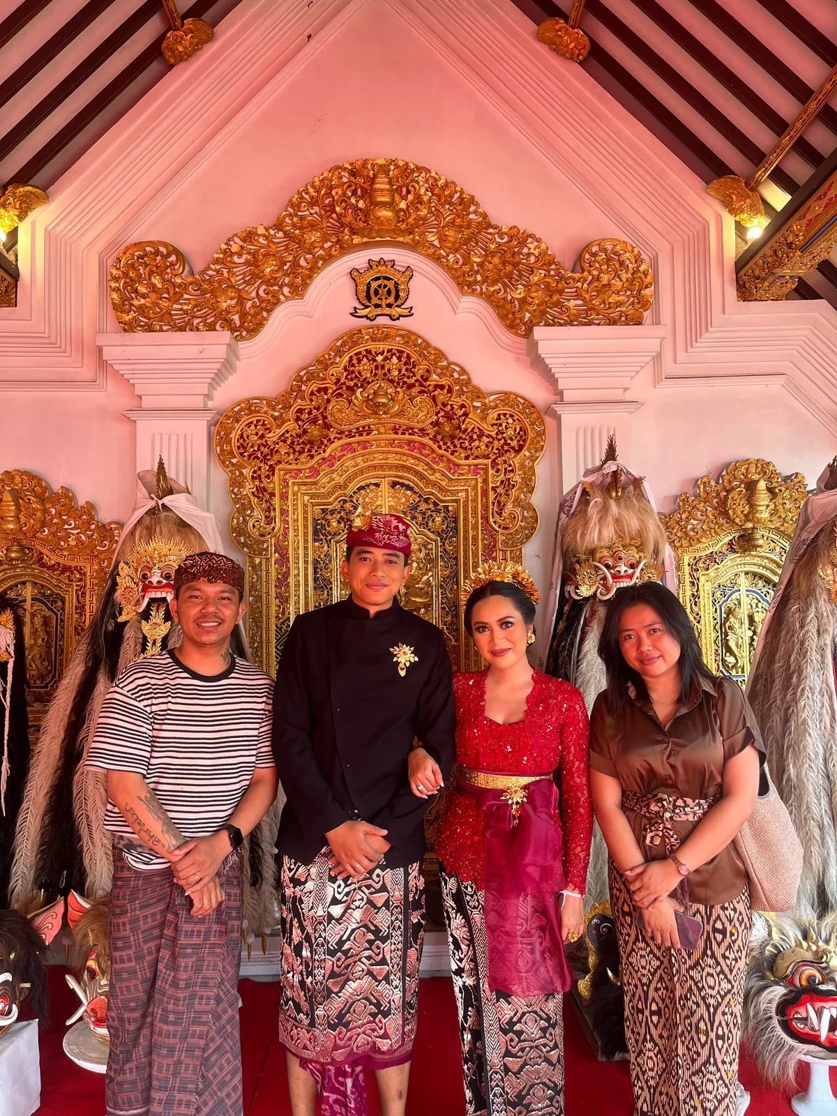 Four people together in front of an ornate Balinese wedding backdrop