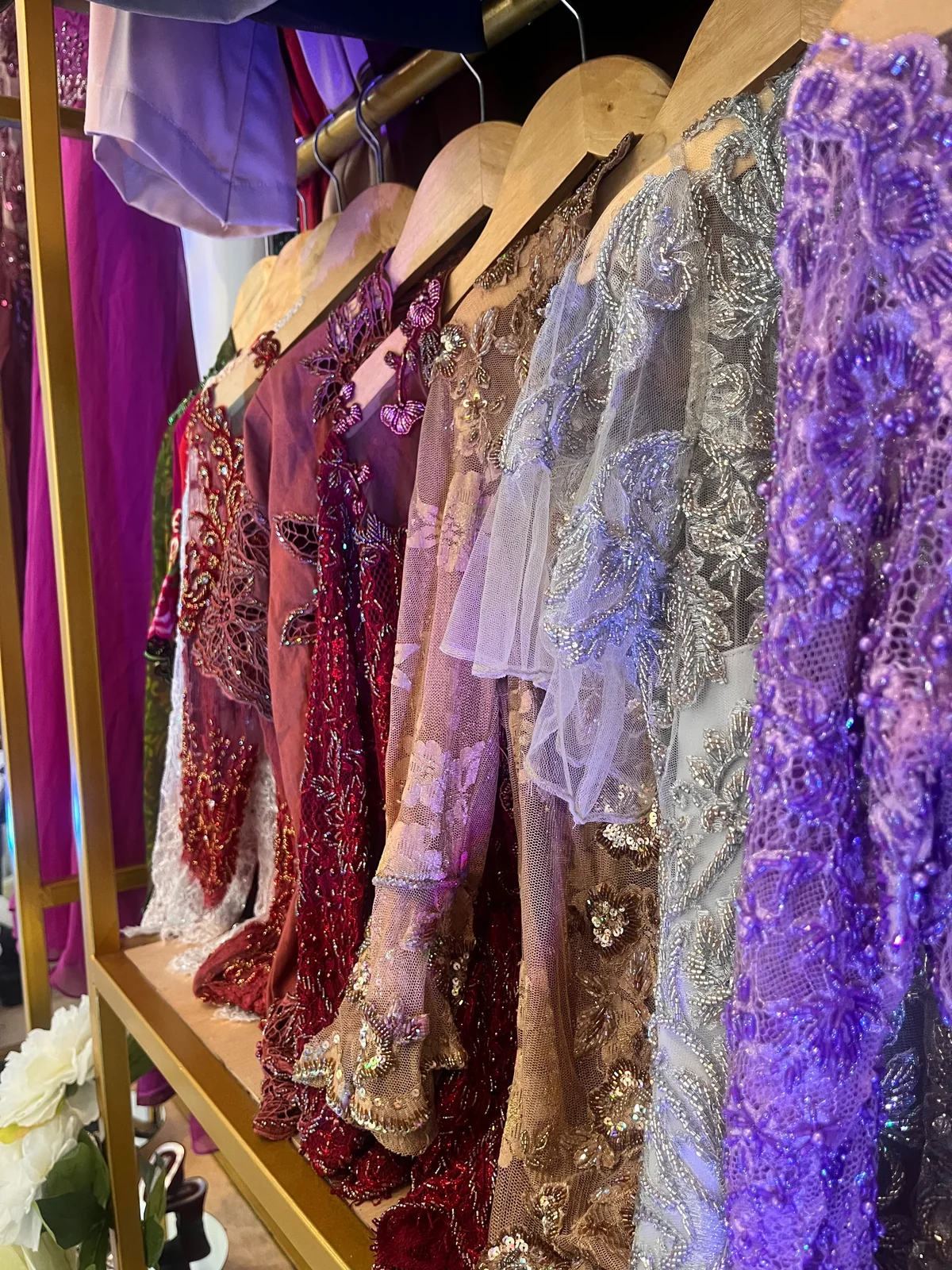 Purple, burgundy, green, and ivory lace garments hanging in the bridal collection